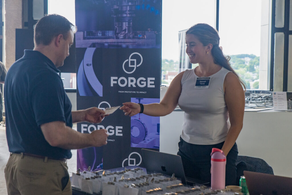 Hanna Torok handing an attendee a guest badge at the FORGE Spring Startup Showcase
